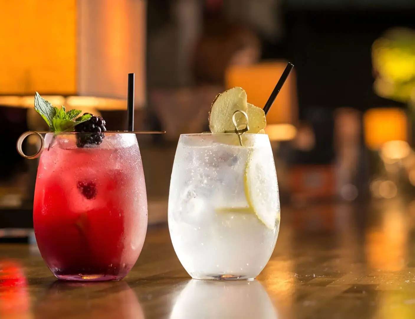 Two drinks are sitting on a table in front of a mirror.